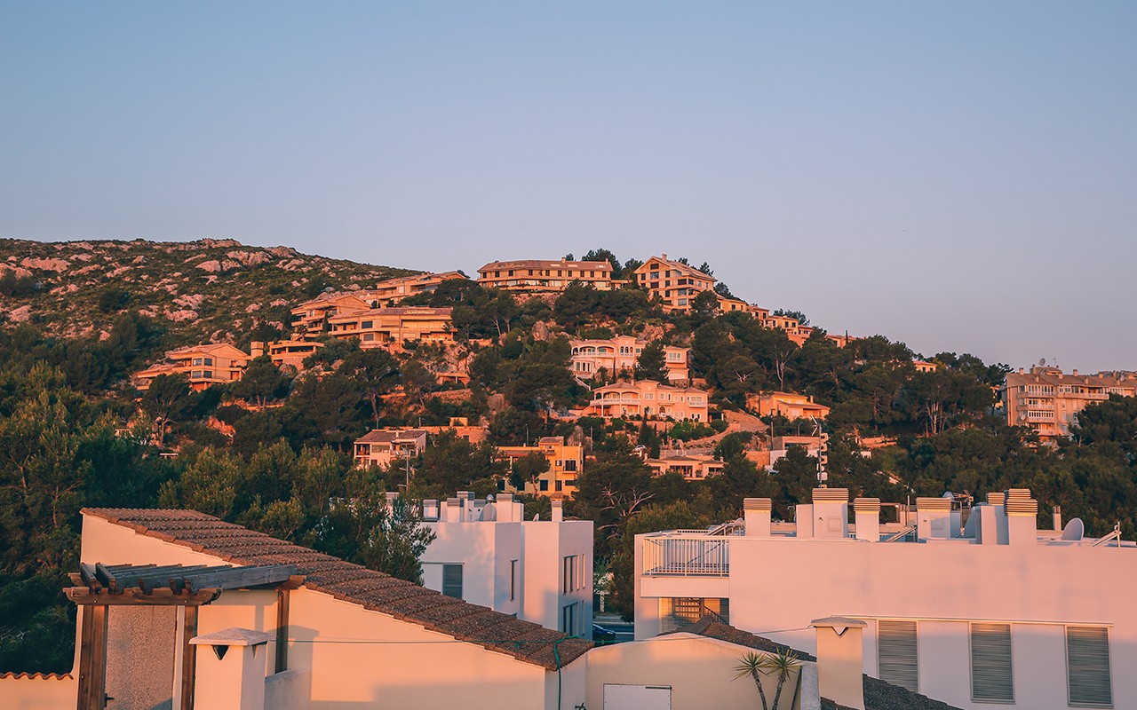 A hillside community of houses basking in the warm glow of the setting sun.