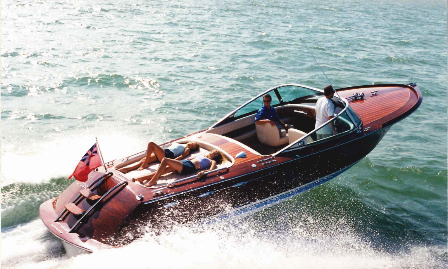 People relaxing aboard a luxurious superyacht tender, gliding smoothly through sparkling waters under a bright, sunny sky.