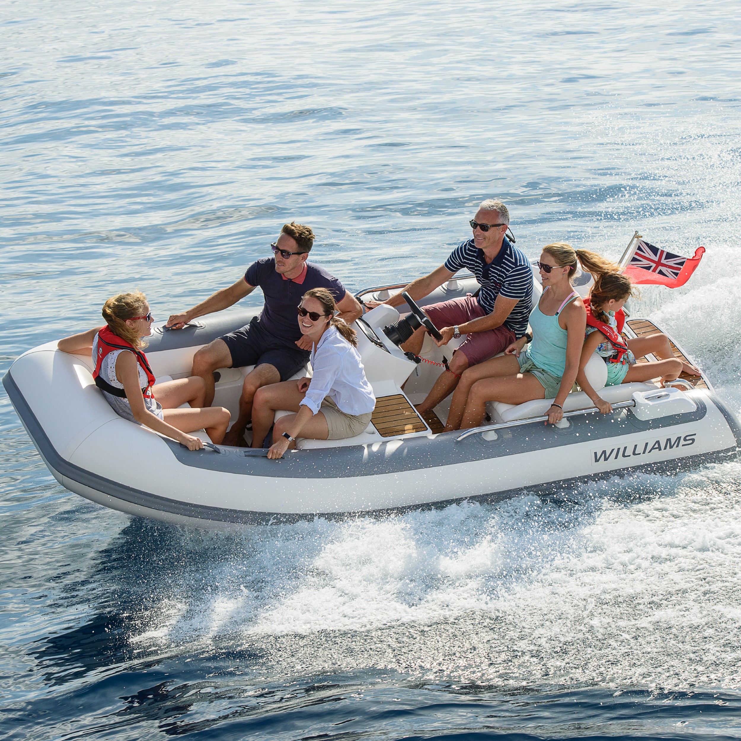 A group of six people enjoying a ride in a midsized yacht tenders on calm waters.