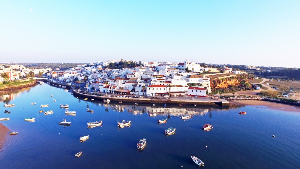 A serene coastal town with white buildings and small boats anchored in calm waters.