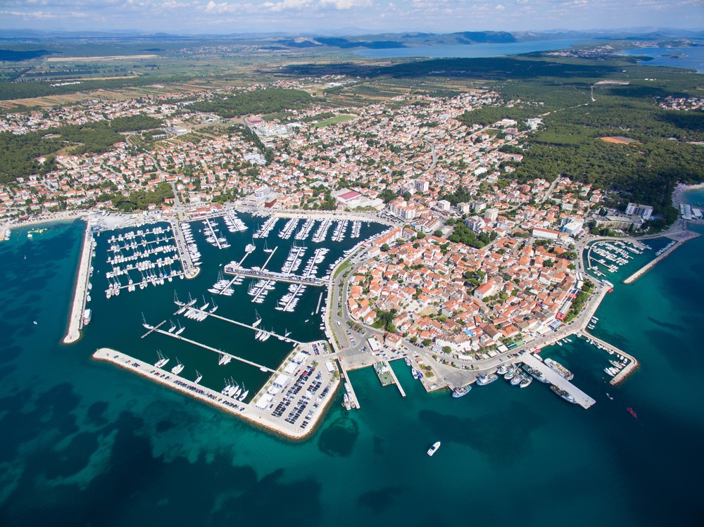 Aerial view of a coastal town with a bustling marina and numerous boats docked.