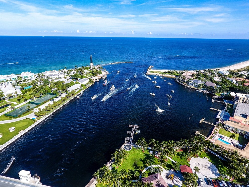 Aerial view of a lively marina with boats, green tennis courts, and beachfront properties.