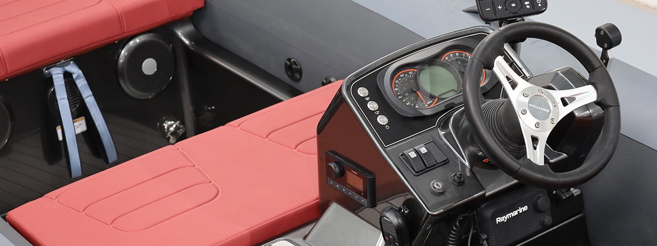 Close-up of the Williams SportJet tender steering wheel and control panel with red seating.