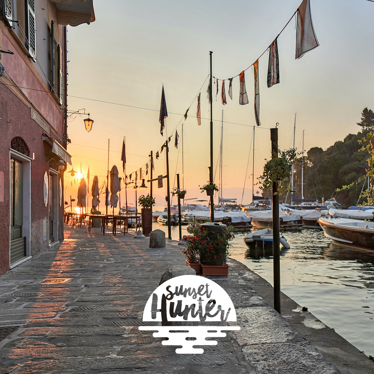 A picturesque marina at sunset with boats docked and a decorated walkway by the water.