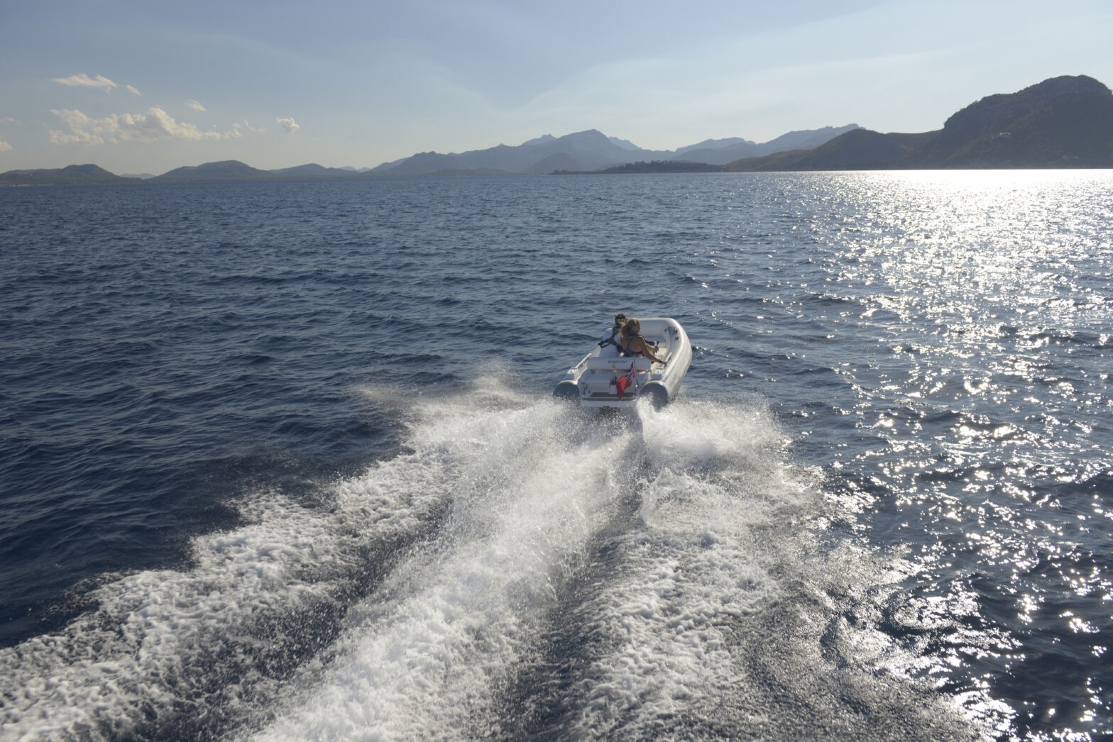 A Williams small jet tender with two people onboard, cruising on calm waters