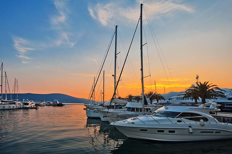 Sunset view with yachts docked and mountains in the background
