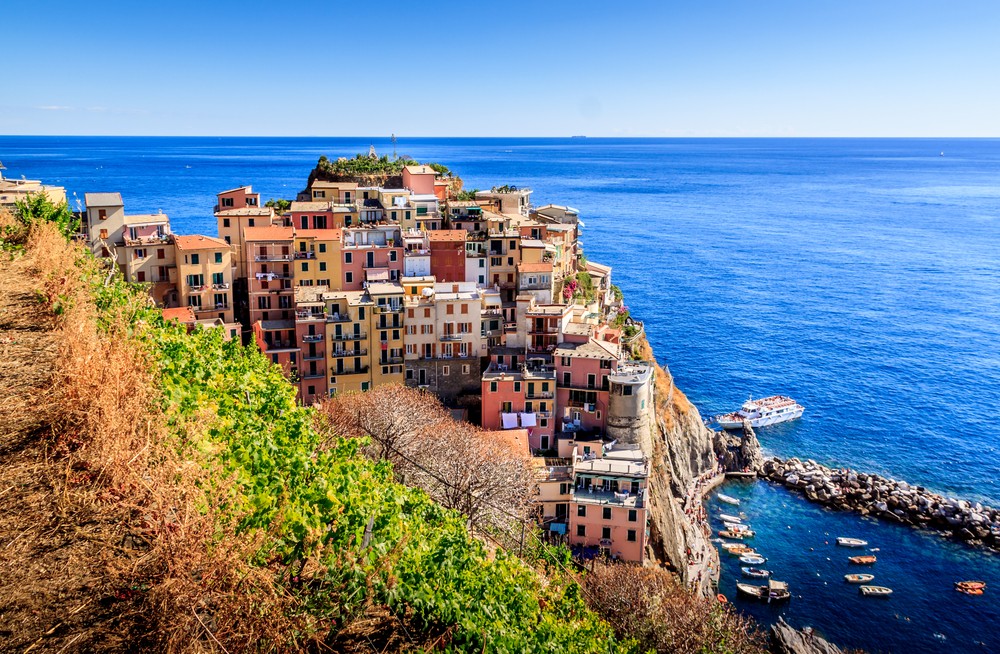 A coastal village with colorful houses perched on a cliff overlooking the blue sea.