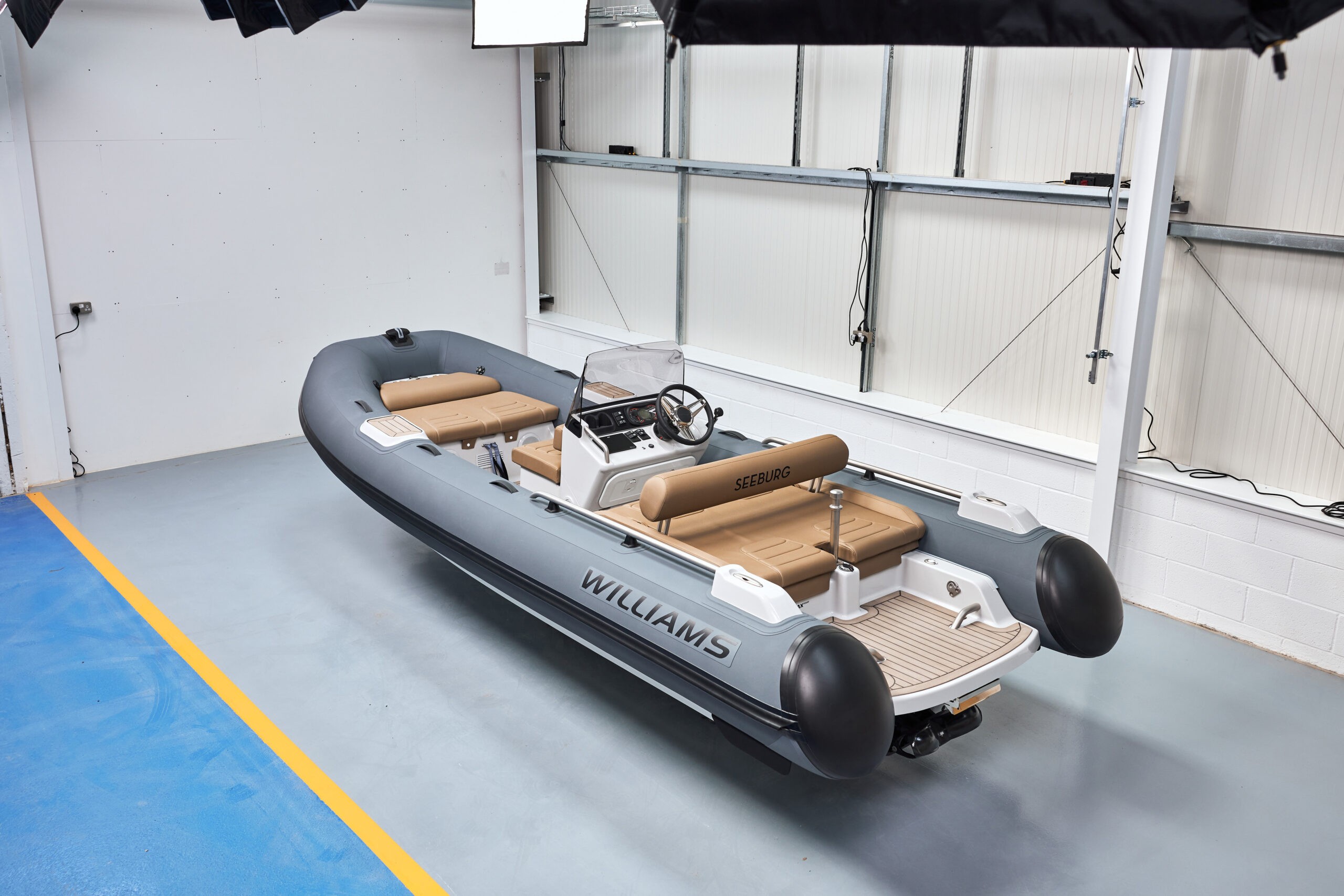 Williams yacht tender with beige seating, steering console, and spacious layout, parked indoors.