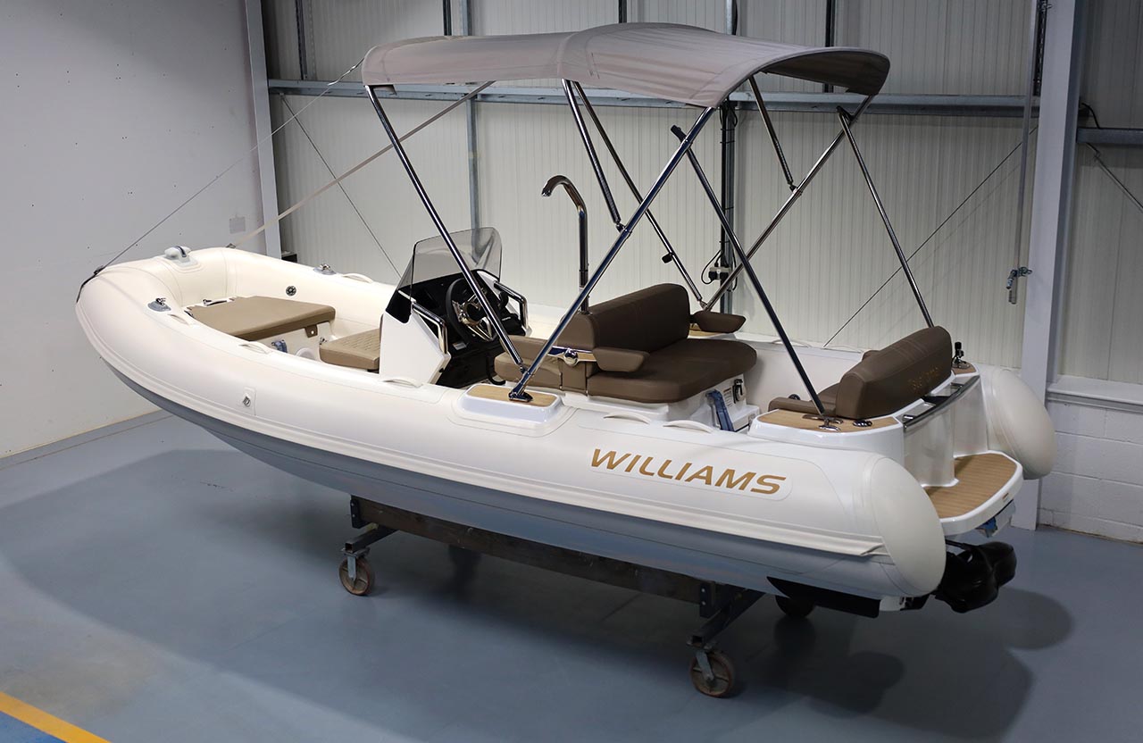 Williams inflatable boat with beige seating and a tan bimini canopy.